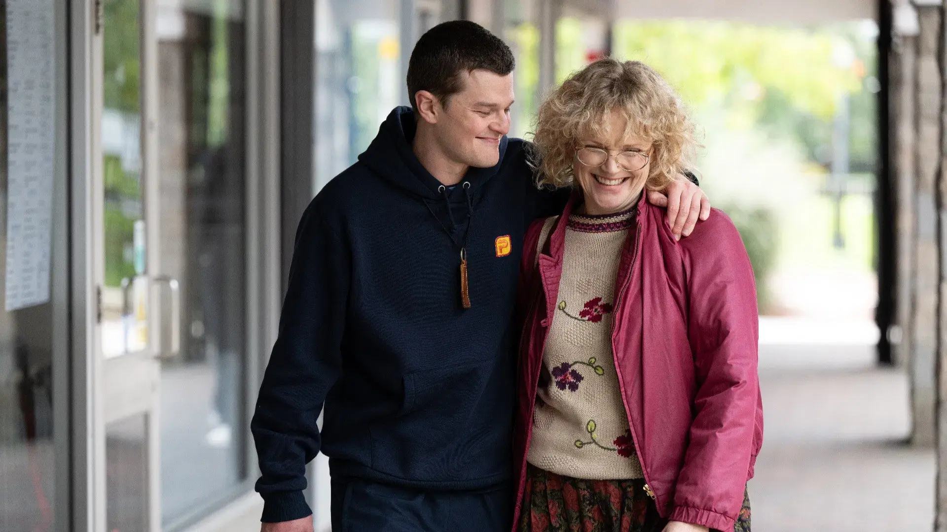 John Davidson (Robert Aramayo) walks smiling with his arm around Dottie (Maxine Peake) – good.film I Swear film guide
