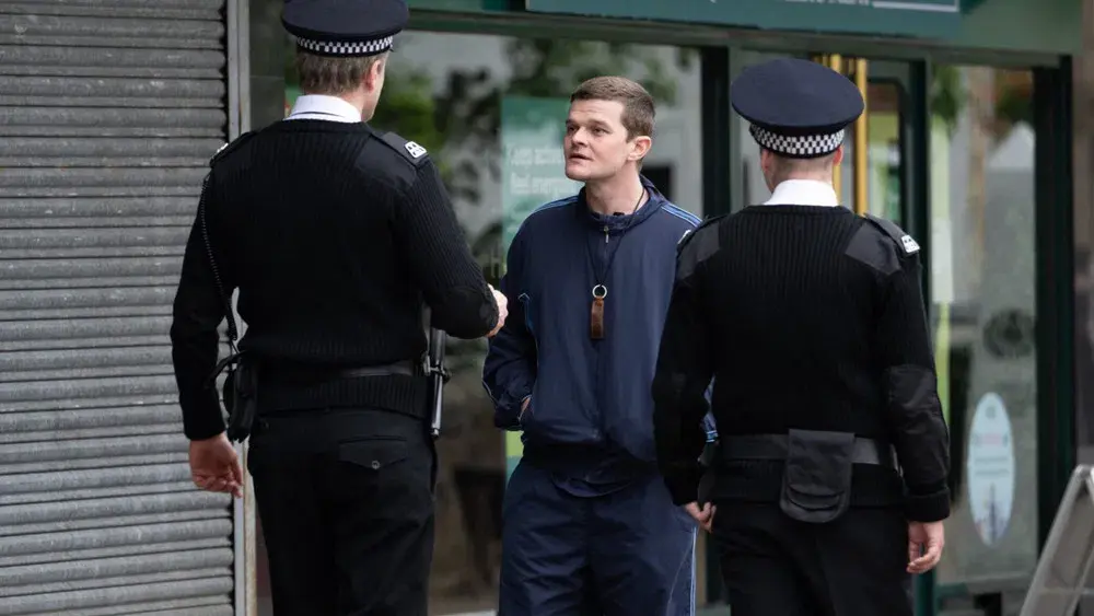 John Davidson (Robert Aramayo) confronted by police officers on a street in I Swear – good.film film guide