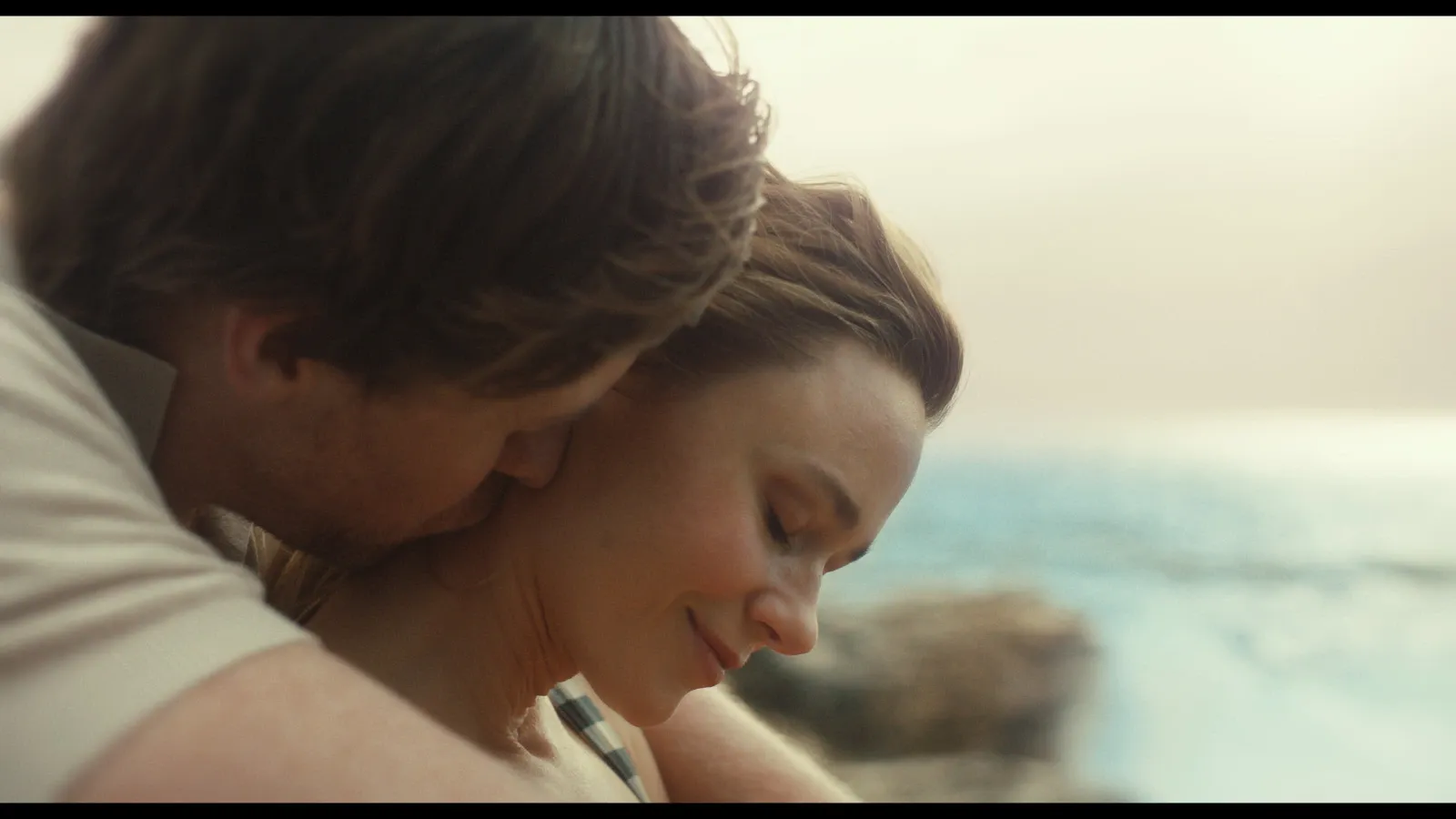 Jake (Alexander England) embraces a smiling Sarah (Maeve Dermody) by the beach