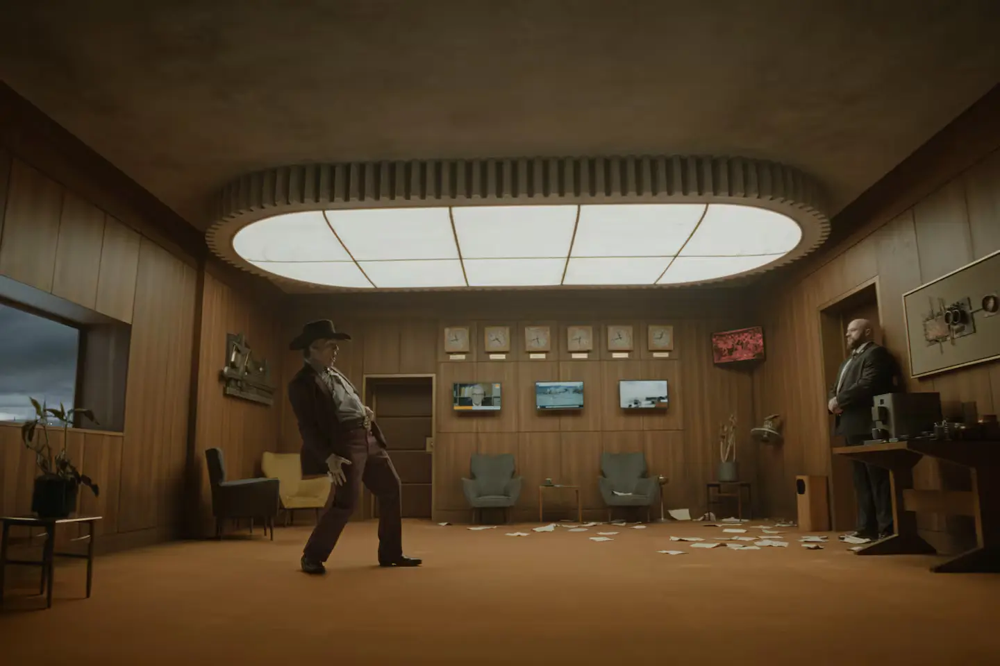 Tom Cruise in Digger in a red suit, in a stylised orange room with overhead lighting